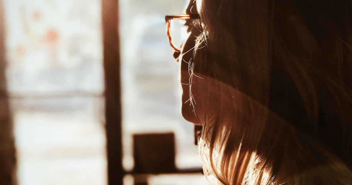 Woman looks out window, worried about eviction from the suite she rents in Vancouver.